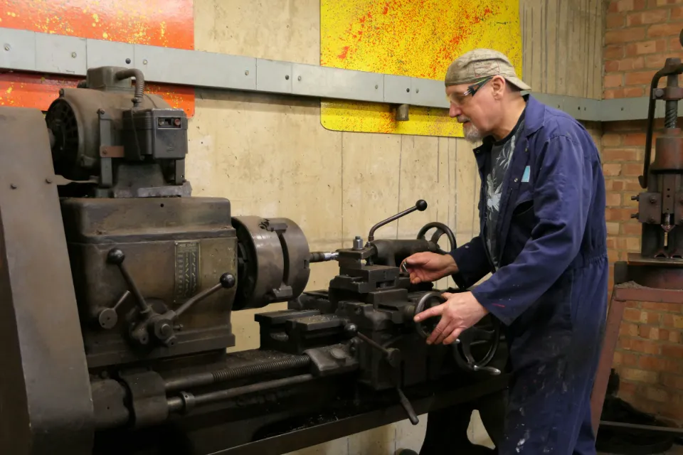 Ein Techniker in Arbeitskleidung arbeitet an einer älteren Maschine