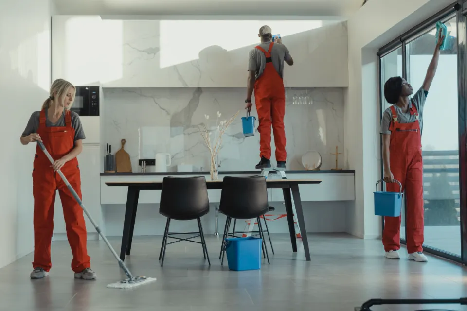 Ein Reinigungsteam in Arbeitskleidung reinigt eine helle Wohnküche